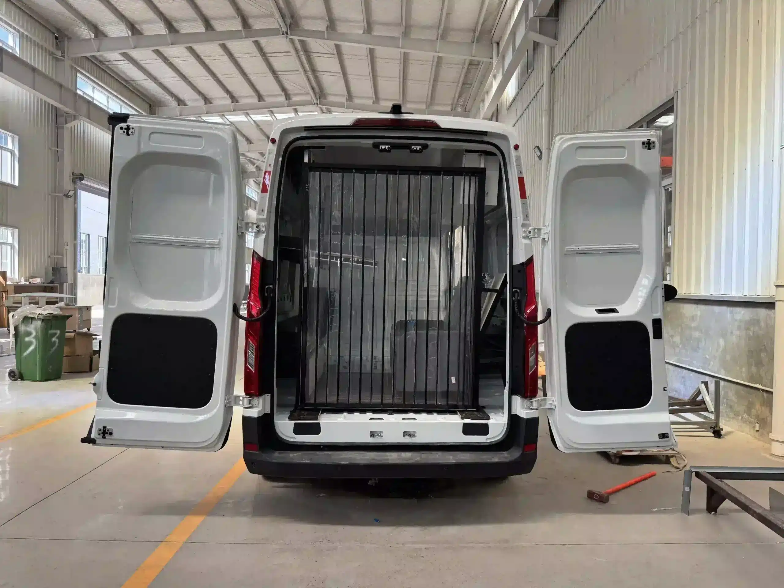 Geöffneter Transporter mit eingebautem Camping-Modul VANBOX RV Home Box in einer Werkstatthalle