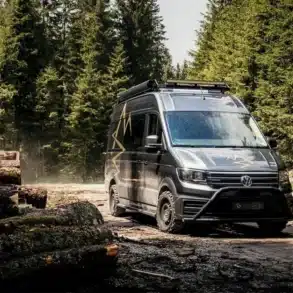 Der Aquila Adventure Creston Crafter 4x4 fährt auf einer schlammigen Waldstraße zwischen gefällten Baumstämmen.
