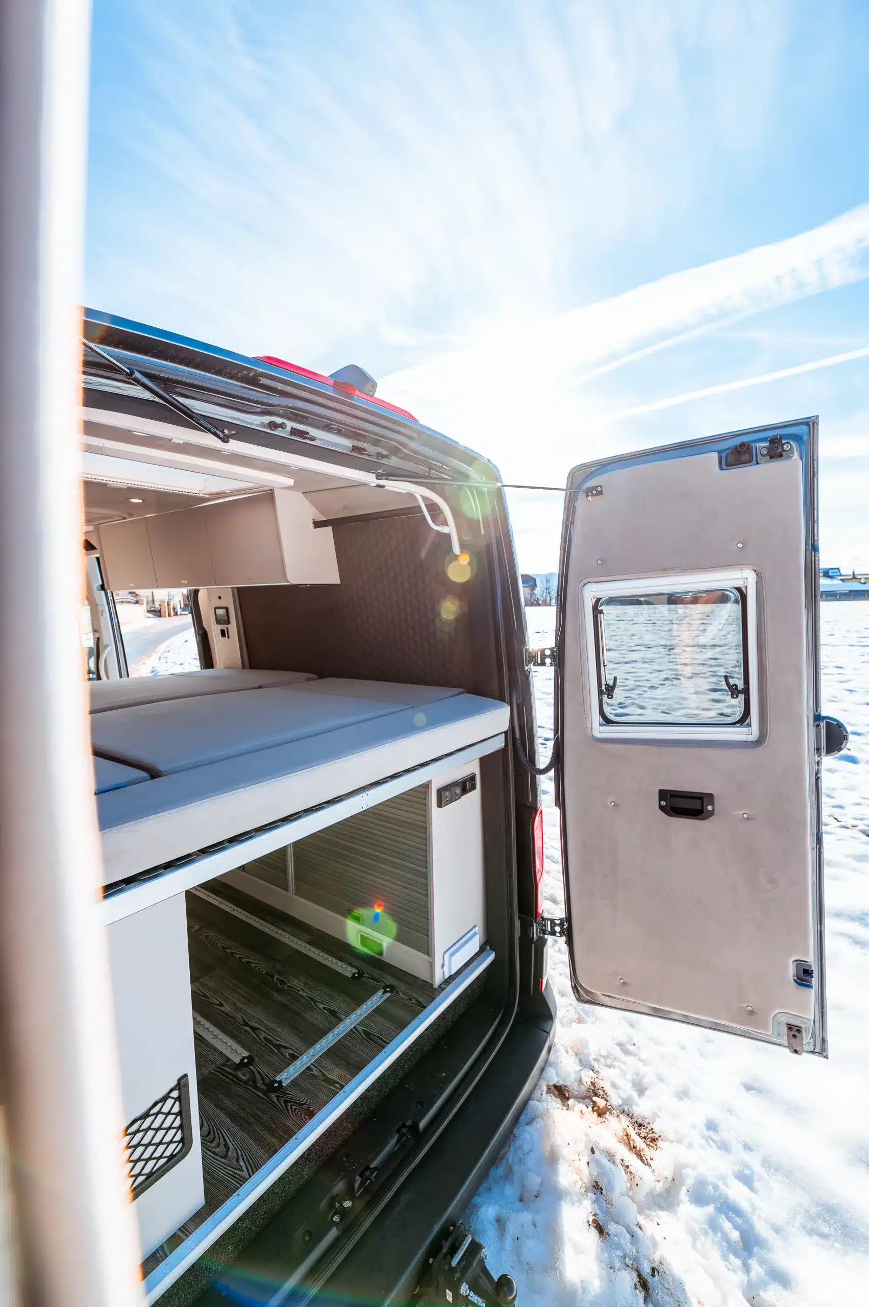 Stauraum und Bett im Heck des Aquila Adventure Creston Crafter 4×4 mit weit geöffneter Tür im Schnee