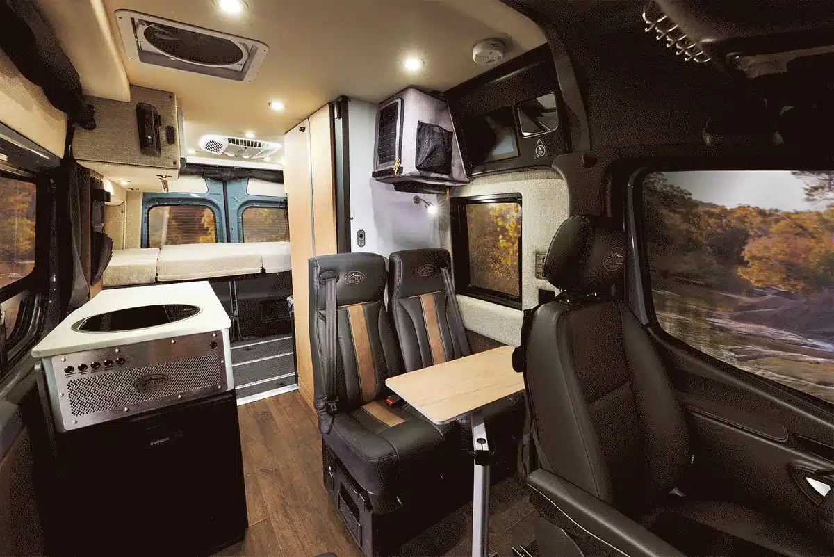 Innenansicht des 2026 Beast Mode XO Campervans mit Sitzbank, Küchenzeile und Stauraum.