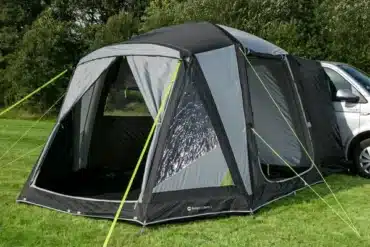 Das Berger Liberta Air freistehende Busvorzelt aufgebaut neben einem Campervan auf einer Wiese.