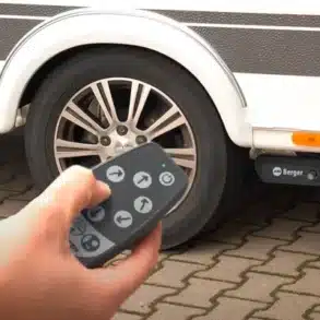 Person steuert mit Fernbedienung eine Berger Titanium oder Platinum Rangierhilfe an einem Wohnwagenrad.