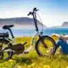 Blaupunkt Emmi faltbares E-Bike 20 Zoll 250W steht auf einer Wiese vor einer Frau mit Seeblick