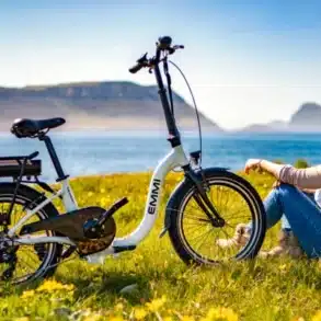 Blaupunkt Emmi faltbares E-Bike 20 Zoll 250W steht auf einer Wiese vor einer Frau mit Seeblick