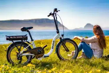 Blaupunkt Emmi faltbares E-Bike 20 Zoll 250W steht auf einer Wiese vor einer Frau mit Seeblick