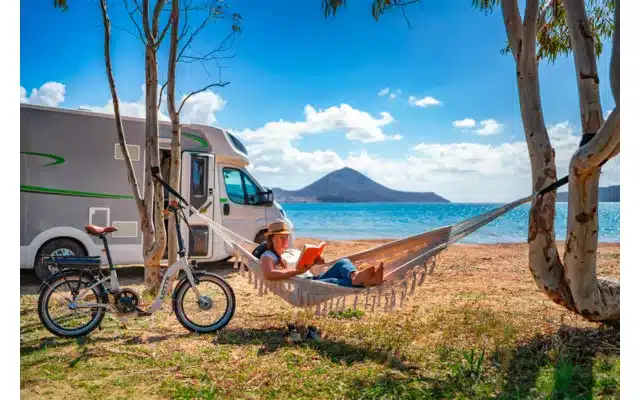 Blaupunkt Lotte faltbares E-Bike neben Wohnmobil und Hängematte am Wasser