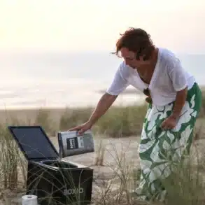 Frau befüllt eine BOXIO Trenntoilette im Freien am Strand mit Einstreu.