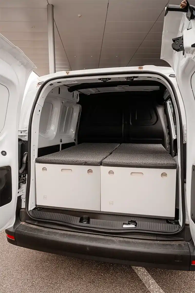 Der Camper Lite von CUBE4LIFE als modulares Camping-Set im Laderaum eines weißen Transporters mit aufgeklappter Hecktür.