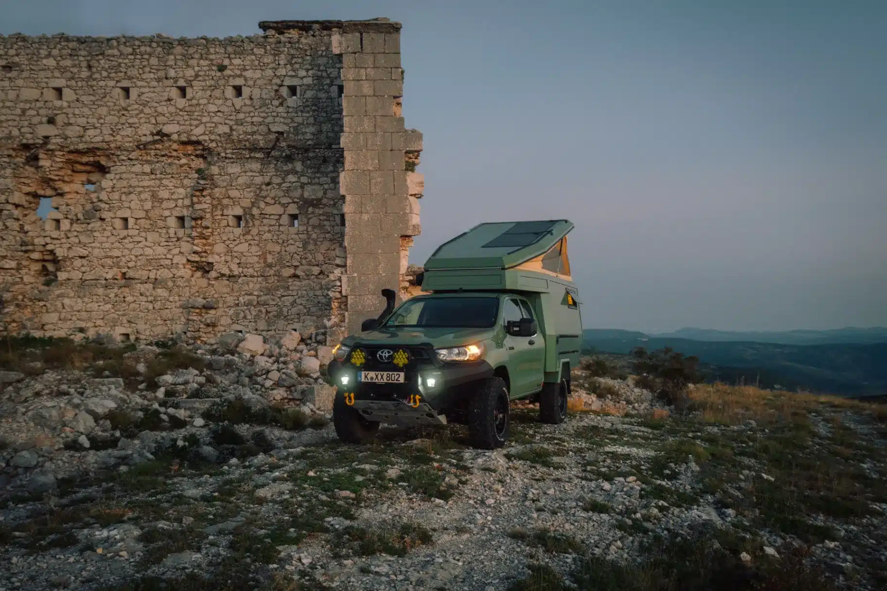 Offroad-Pickup mit Trailcat-Kabine von Ellie Overland vor einer Steinruine in rauer Natur
