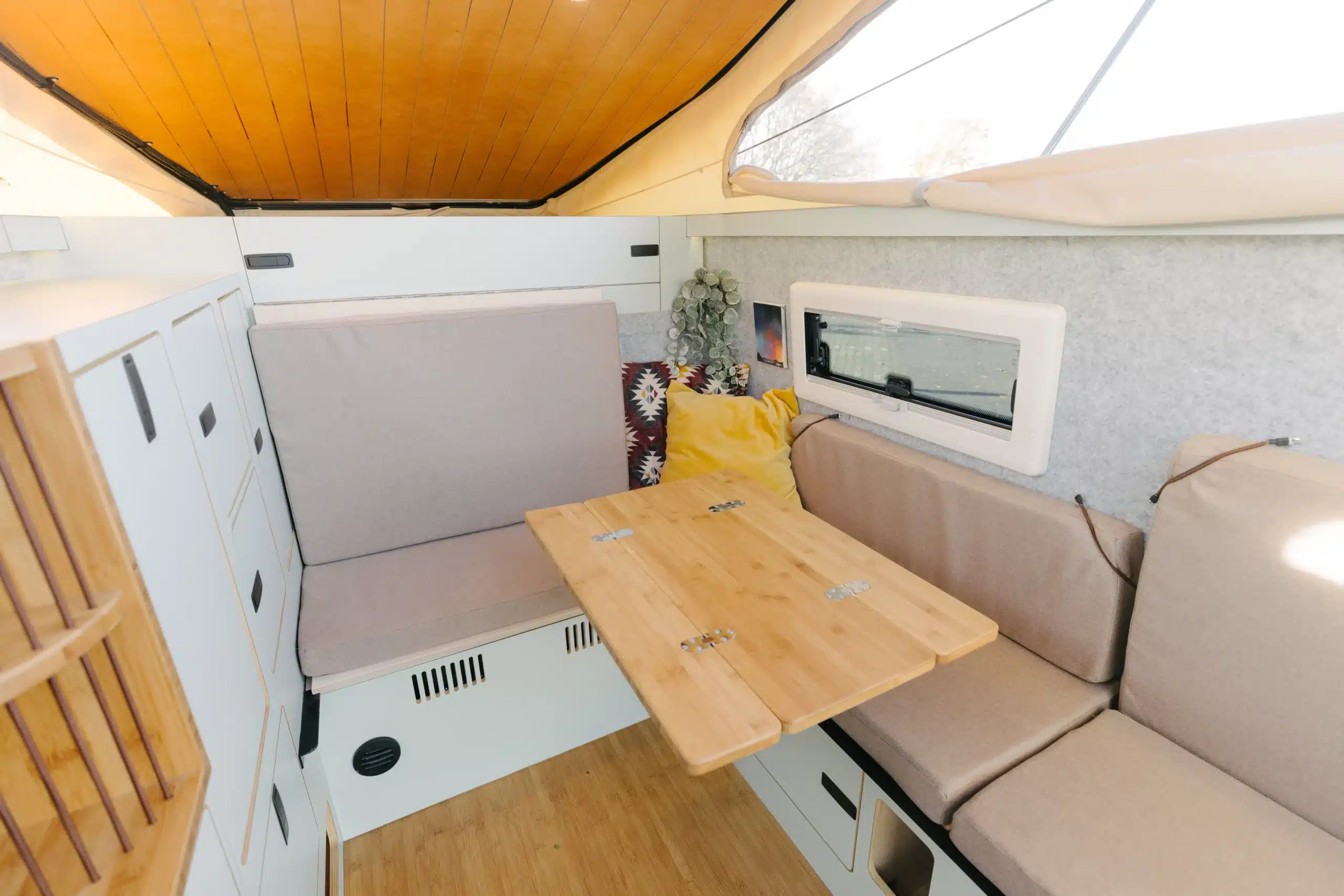 Kompakter Innenraum der Trailcat Pickup-Kabine mit Sitzbank, Tisch und Stauraum