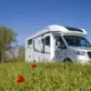Exclusiv Lindau JF Reisemobil auf Mercedes Sprinter Basis steht auf einer Wiese mit Mohnblumen unter blauem Himmel.
