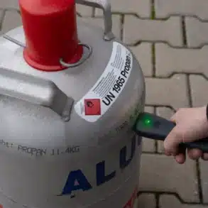 Hand hält Berger CH410 Gascontrol an eine Propan-Gasflasche zur Füllstandsmessung