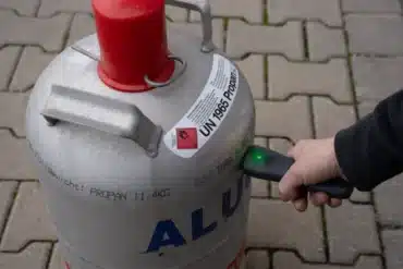 Hand hält Berger CH410 Gascontrol an eine Propan-Gasflasche zur Füllstandsmessung