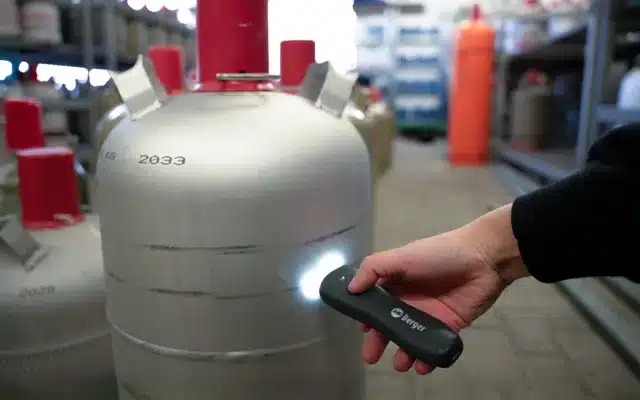 Hand hält Berger CH410 Gascontrol an eine große LPG-Gasflasche zur Füllstandsmessung mit eingeschaltetem Licht