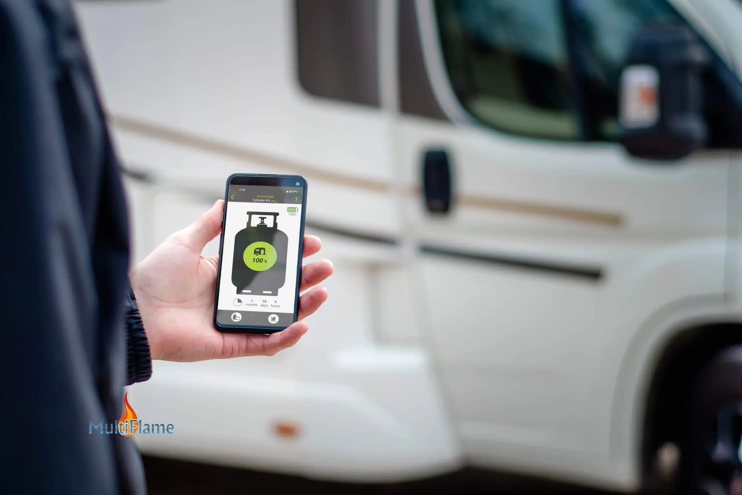 Hand hält Smartphone mit App zur Füllstandsanzeige einer Gasflasche vor Wohnmobil.