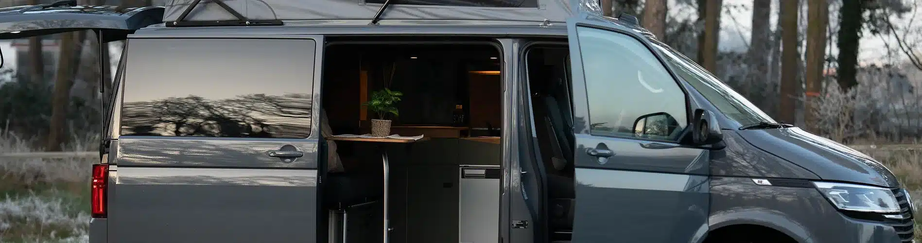 Grauer Transporter mit geöffneten Türen und sichtbarem Innenausbau JUBO Campingausbau VANactive