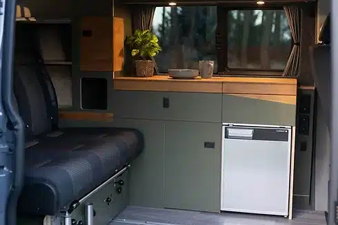 Innenraum eines Vans mit JUBO Campingausbau, Küchenzeile, Schlaf-Sitzbank und Kompressorkühlschrank