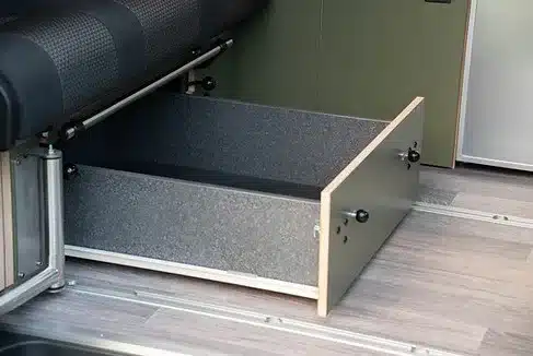 Offene Schublade unter der Schlaf-Sitzbank des JUBO Campingausbaus VANactive, ideal für Stauraum im Camper.