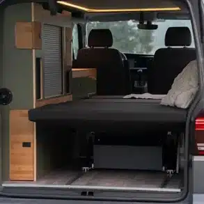 Innenraum eines ausgebauten Vans mit Schlaf-Sitzbank, Stauraumlösungen und moderner Beleuchtung