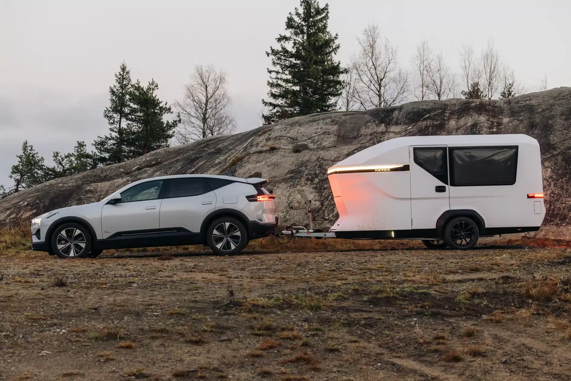 Karoo Camper, ein leichter Mikro-Wohnwagen, hinter einem modernen Auto in natürlicher Umgebung.