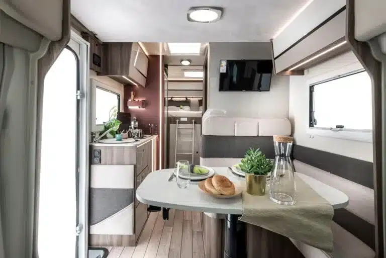 Innenraum eines Kronos Fit Reisemobils mit Sitzgruppe, Küche und modernem Interieur.