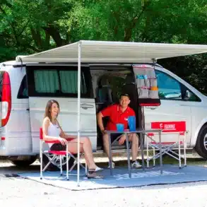 Kompatker Campervan mit ausgefahrener Fiamma F35 Pro Markise, darunter zwei Personen beim Camping