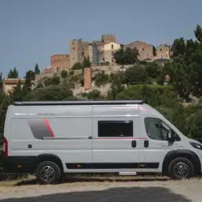 Seitenansicht des Livingstone Sport DUO XL Kastenwagens, geparkt vor einer Burg und von Bäumen umgeben.