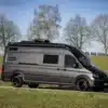 Schwarzer MAN TGE Next Level 6,80 m Van auf Wiese, ideal für den Ausbau als Reisemobil