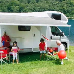 Fiamma F45s Markise am Wohnmobil, aufgespannt mit Familie beim Camping am See