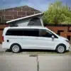 Mercedes-Benz V-Klasse Vanstar Campervan mit offenem Aufstelldach, Seitenansicht auf Straße.