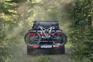 Thule Epos Fahrradträger mit zwei E-Bikes an einem Camper auf einem Waldweg im Grünen.