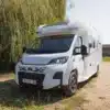 Teilintegriertes Wohnmobil Notin Progress Malaga CF geparkt vor Bäumen auf einem sonnigen Platz