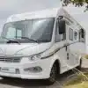 Frontansicht eines Notin Rubi JF vollintegrierten Wohnmobils mit weißem Aufbau auf einer Landstraße.