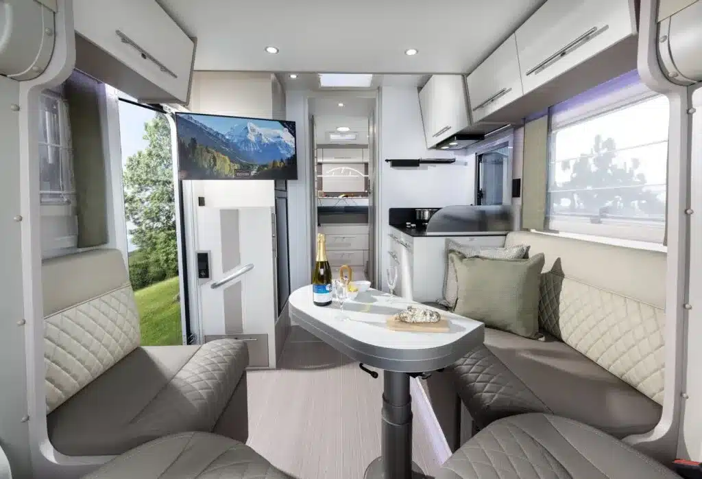 Moderner Salon mit großzügiger Sitzgruppe und Sicht auf Küche und Einbauten im Notin Vitoria Reisemobil