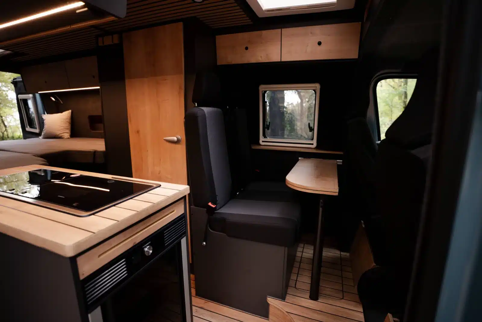 Innenansicht des Renault Master VANtastic mit Küchenblock, Dinette und Bett im Hintergrund.