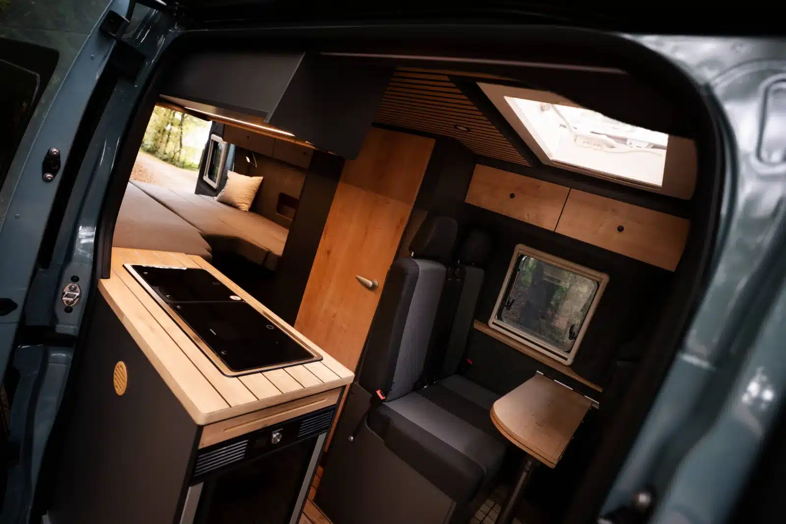 Innenraum des Renault Master VANtastic mit Küchenblock, Sitzgruppe und großem Längsbett.