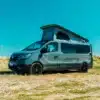 Renault Trafic BS-CAMP Campervan mit geöffnetem Aufstelldach, seitliche Ansicht auf Wiese an einem sonnigen Tag