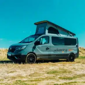 Renault Trafic BS-CAMP Campervan mit geöffnetem Aufstelldach, seitliche Ansicht auf Wiese an einem sonnigen Tag