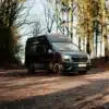 Schwarzer Renault Trafic Campervan, geparkt auf einem Waldweg