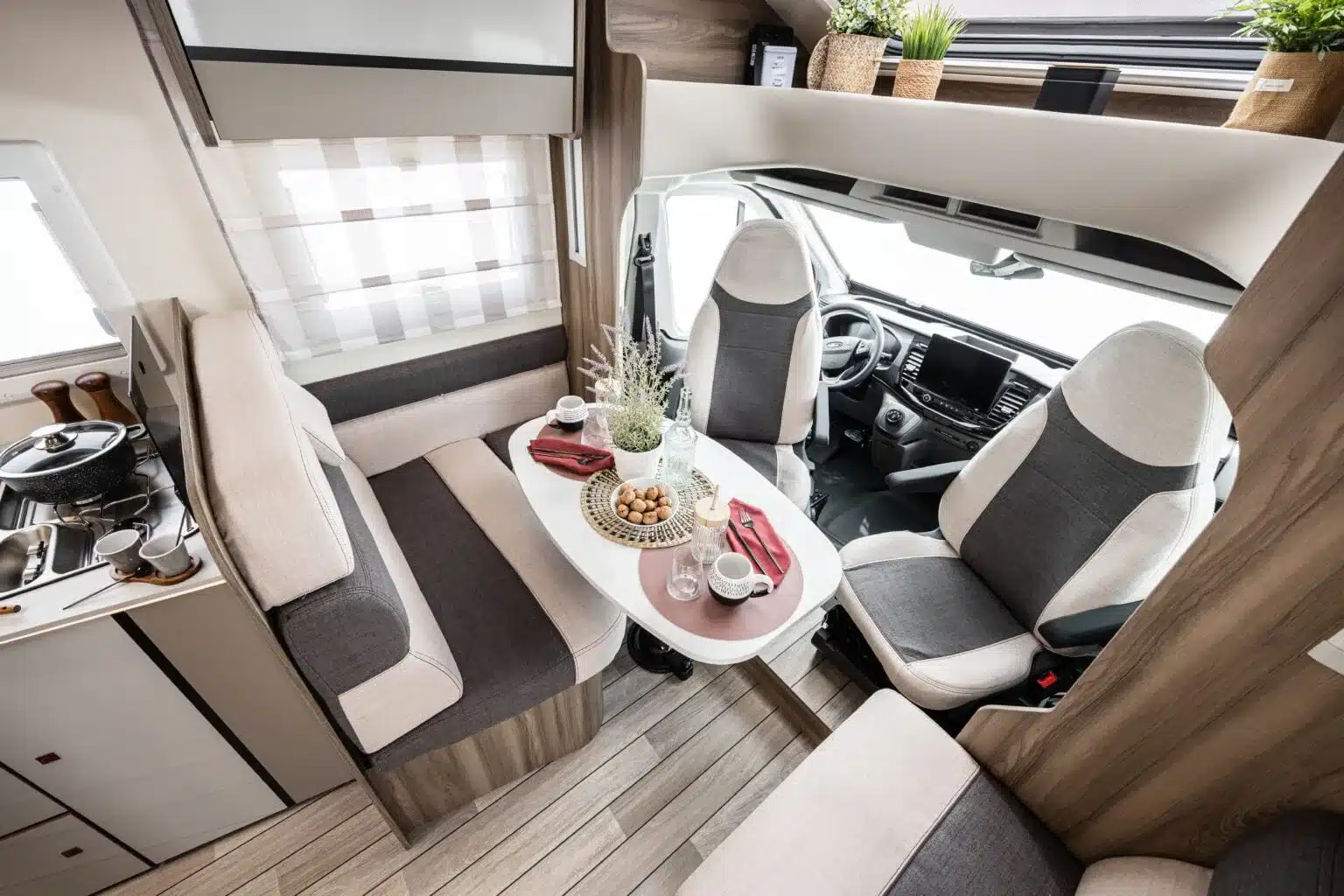 Der Innenraum des Kronos 285 TL Reisemobils mit Sitzgruppe, Tisch und Fahrerhaus auf Ford Transit Basis