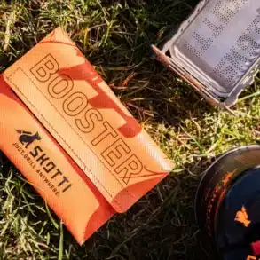 SKOTTI Faltbarer Campinkocher Booster mit orangefarbener Tasche und Zubehör auf Gras