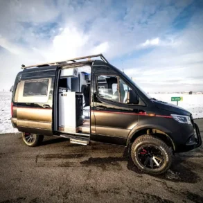 Mercedes-Benz Sprinter 6,0 m Kastenwagen-Ausbau von VR Motorhomes, Allrad, vor verschneiter Winterlandschaft, Schiebetür geöffnet, Innenraum sichtbar.