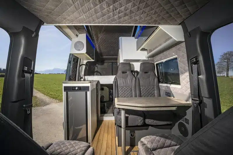 Innenansicht des ausgebauten Mercedes-Benz Sprinter 6,0 m von VR Motorhomes mit Sitzgruppe und Möbeln.