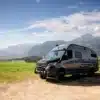 Sprinter 7 m Campervan auf einem Feldweg mit Bergen im Hintergrund