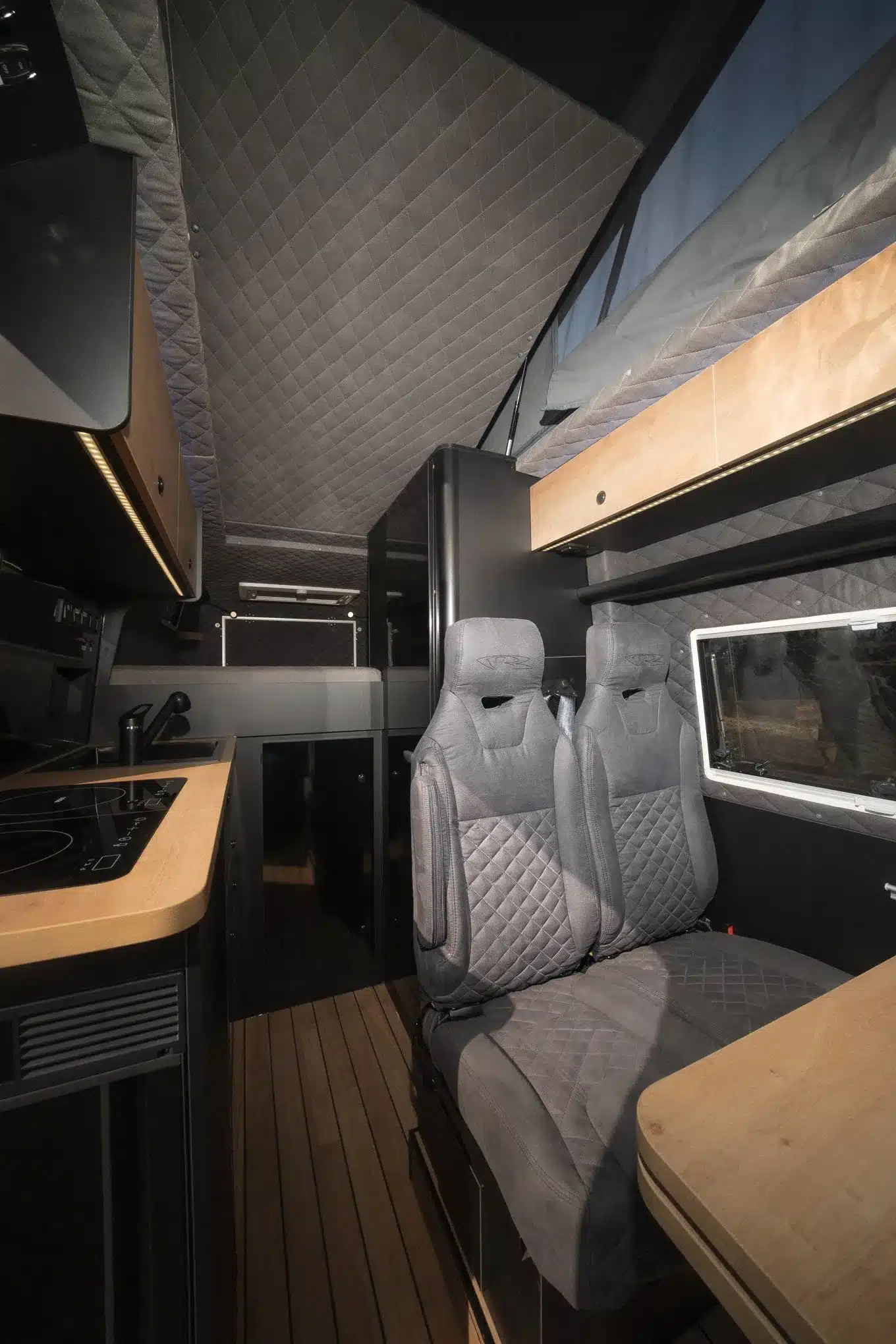 Wohnbereich eines Sprinter 7 m Campers mit Aufstelldach und zwei Sitzen