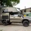 Terrafox Wohnkabine montiert auf einem Toyota Hilux Pick-up, outdoor-tauglich mit Offroad-Reifen, vor Werkstattgebäude