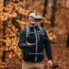 Eine Person hält zusammengefaltete Thermo-Sitzkissen von Naturbummler in der Hand, mit herbstlichem Wald im Hintergrund