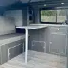 Innenansicht des ausgebauten Transporters mit Küchenzeile, Tisch und Sitzbank – VA101 Basic Campervan-Ausbau.