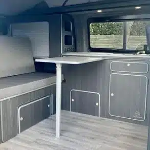 Innenansicht des ausgebauten Transporters mit Küchenzeile, Tisch und Sitzbank – VA101 Basic Campervan-Ausbau.