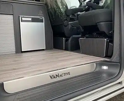 Innenansicht eines für den Alltag und Camping ausgebauten Transporters mit Küchenzeile, Kühlschrank und hochwertigem Boden